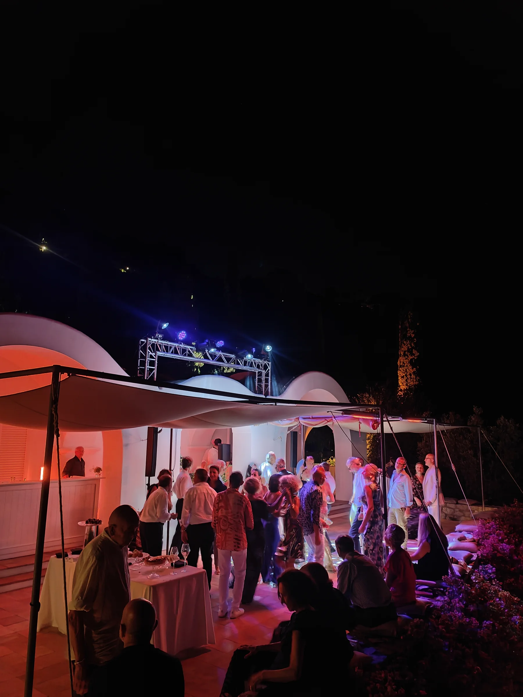 Private dinner under a pergola lit with thousands of fairy lights, with a live singer on stage and a sea view